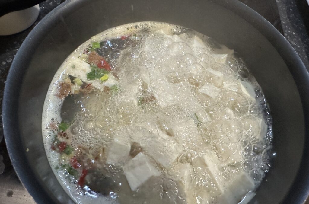 To cook Ottogi the Hot Yeol Ramyeon, Bring 500ml or less of water to a rolling boil in a pot. Add the cubed tofu and let it simmer for 2-3 minutes. This pre-cooks the tofu and infuses it with flavor while creating a slightly richer broth base.