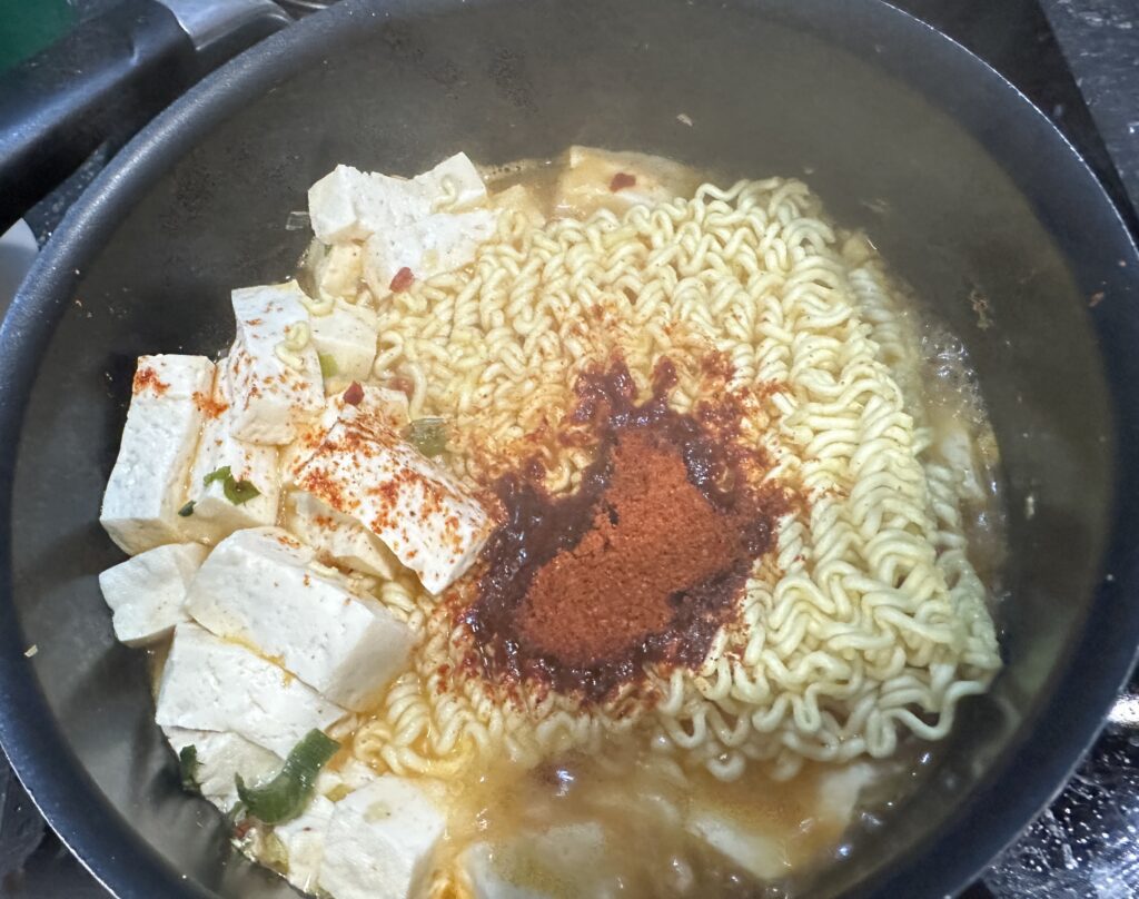 Turn off the heat and add the red spicy powder packet. This is crucial - adding it after turning off heat prevents the spices from burning and maintains the complex flavor profile. Stir thoroughly. If using an egg, crack it in now and stir to create egg ribbons, or leave it whole for a soft-boiled effect.