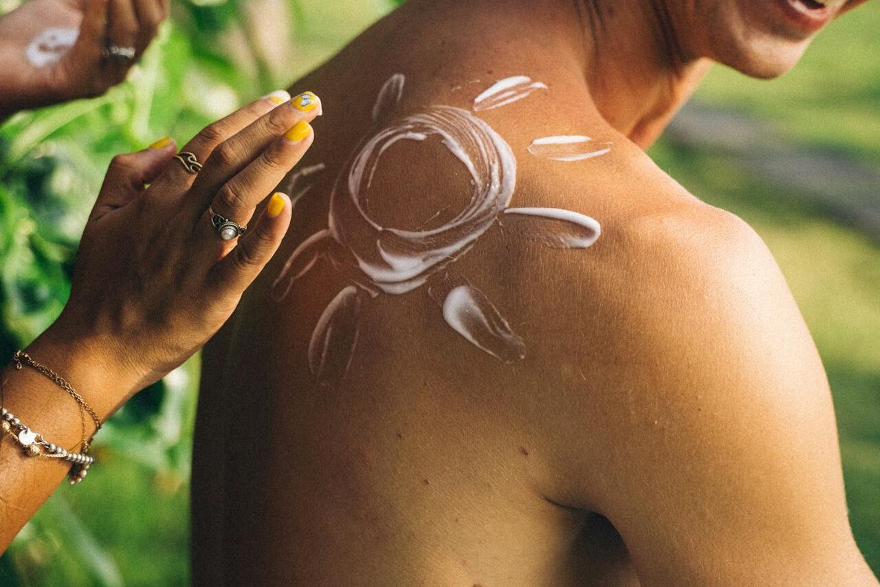 a woman applying sunscreen on a guy's back