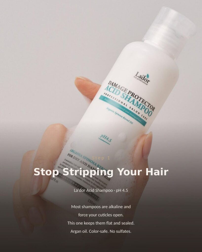 Hand holding La'dor Damage Protector Acid Shampoo 150ml bottle with foam, pH 4.5 sulfate-free Korean shampoo for glass hair